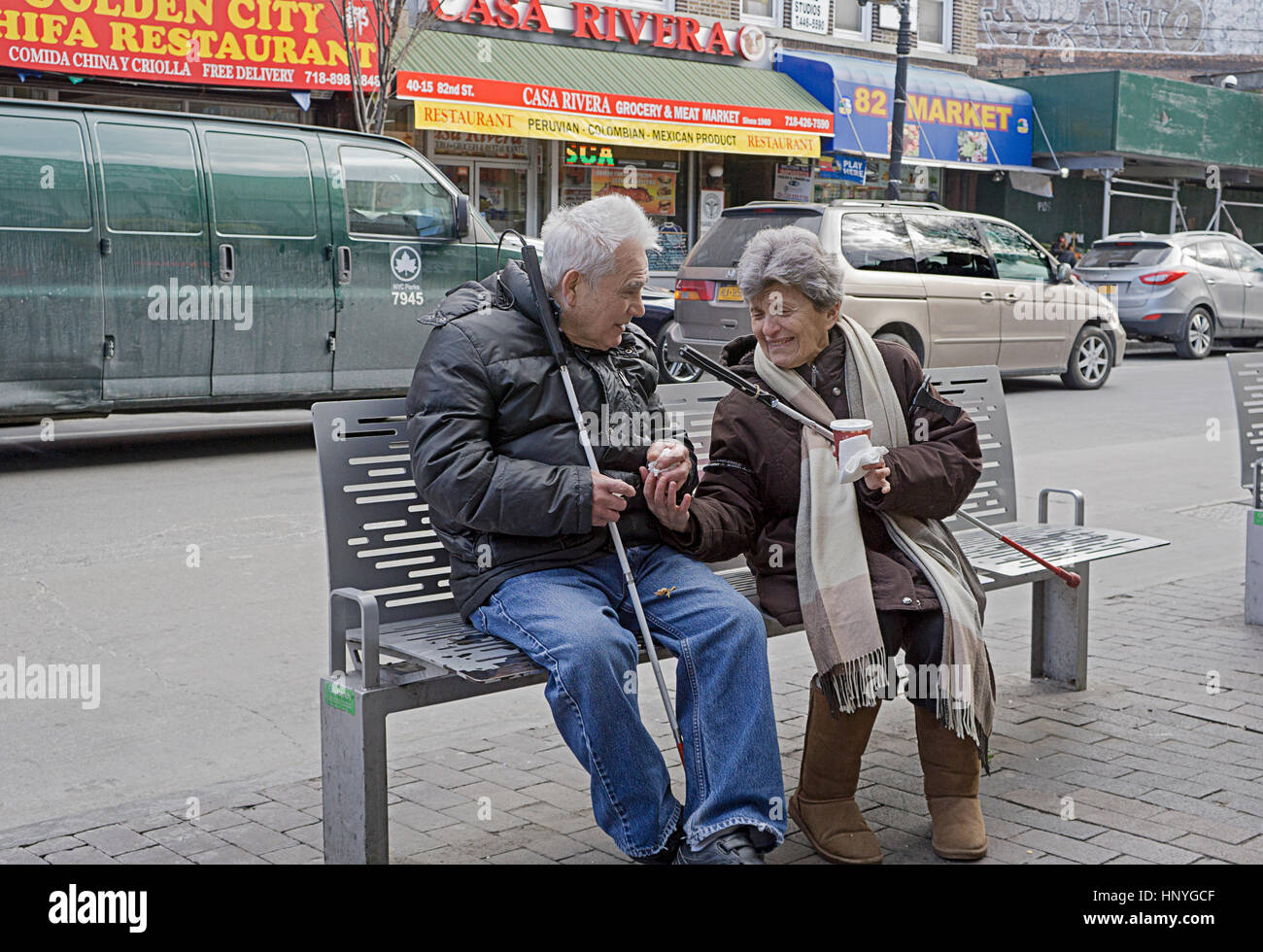 A visually impaired couple seated on a bench in the winter in Jackson Heights Queens New York City Stock Photo