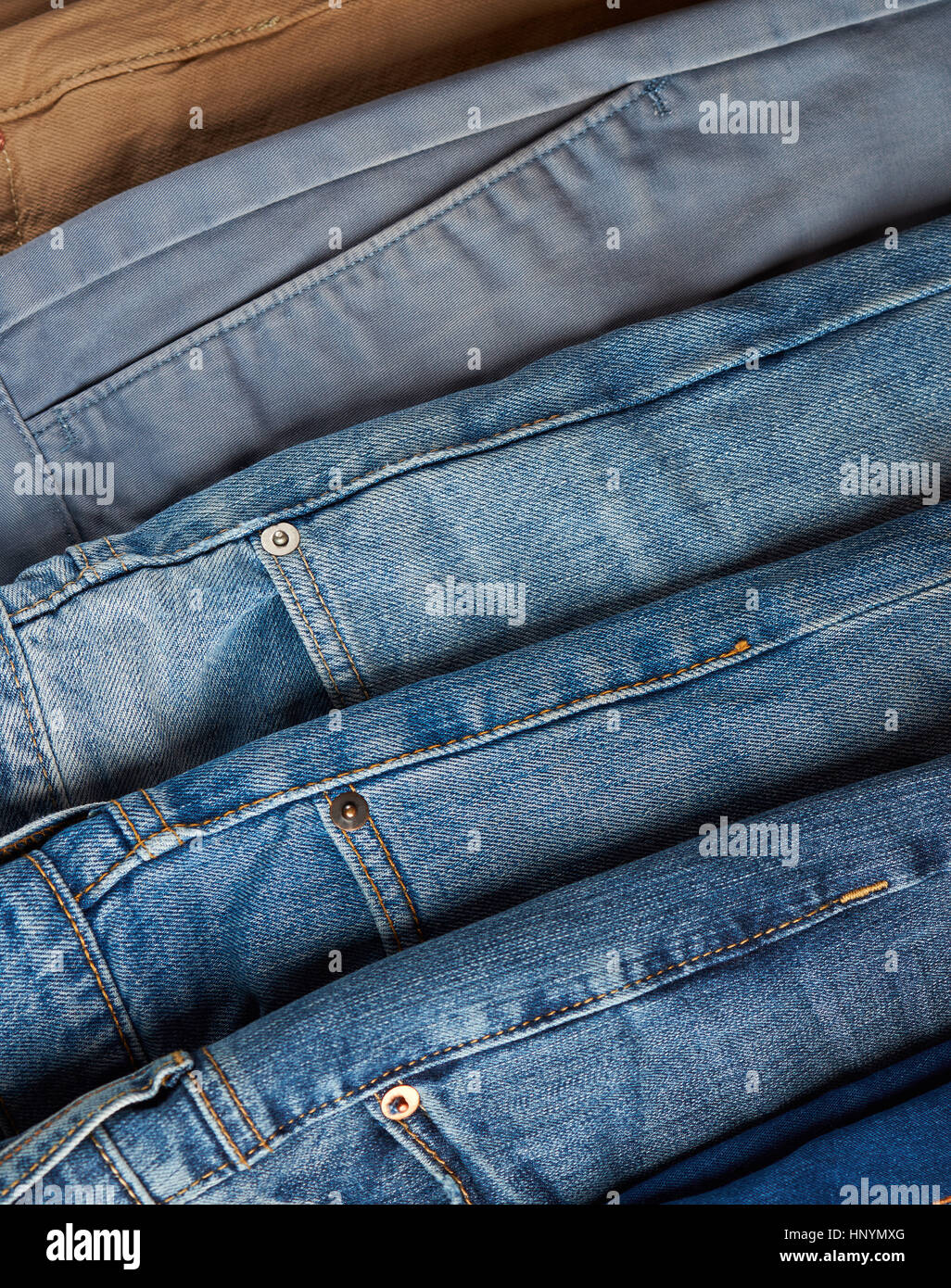Pile of different color jeans view from top. Many pants on shop sale Stock Photo