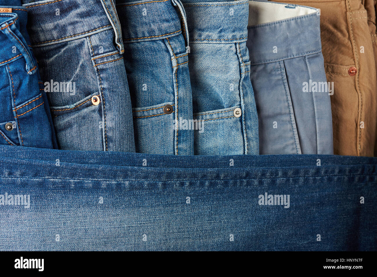 colorful Jeans lay in order view from top. Many pants jeans on shop desk sale Stock Photo