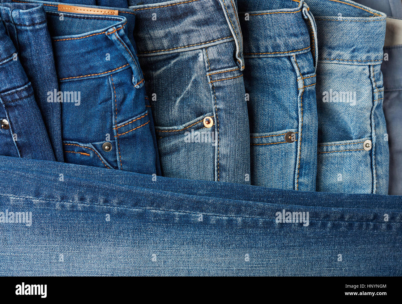Blue jeans pants clothes pile background. Stack of blue jeans on shop desk Stock Photo