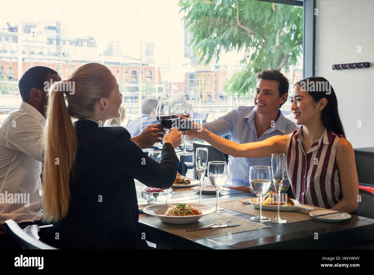 Friends clinking wine glasses in restaurant Stock Photo