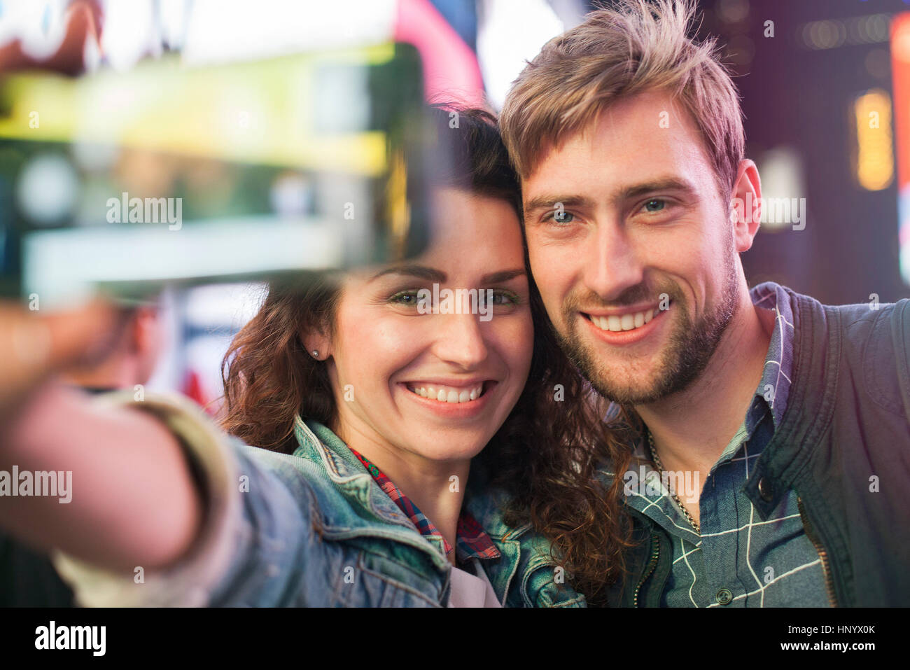 Young couple taking selfie in illuminated city street Stock Photo