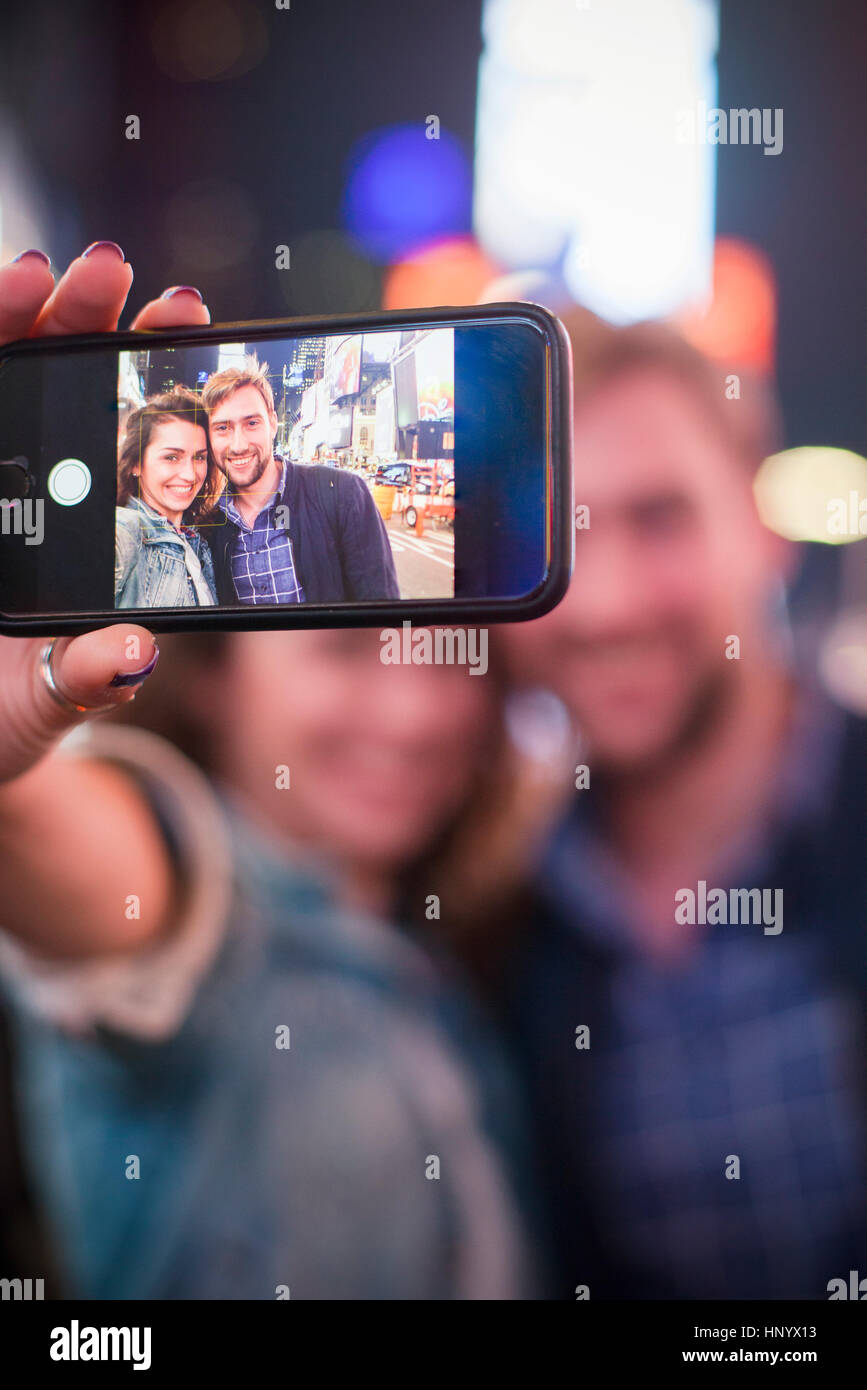 Young couple taking selfie while sightseeing in Times Square, New York City, New York, USA Stock Photo