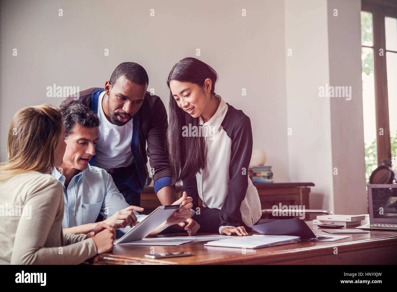 Colleagues looking at digital tablet together in office Stock Photo