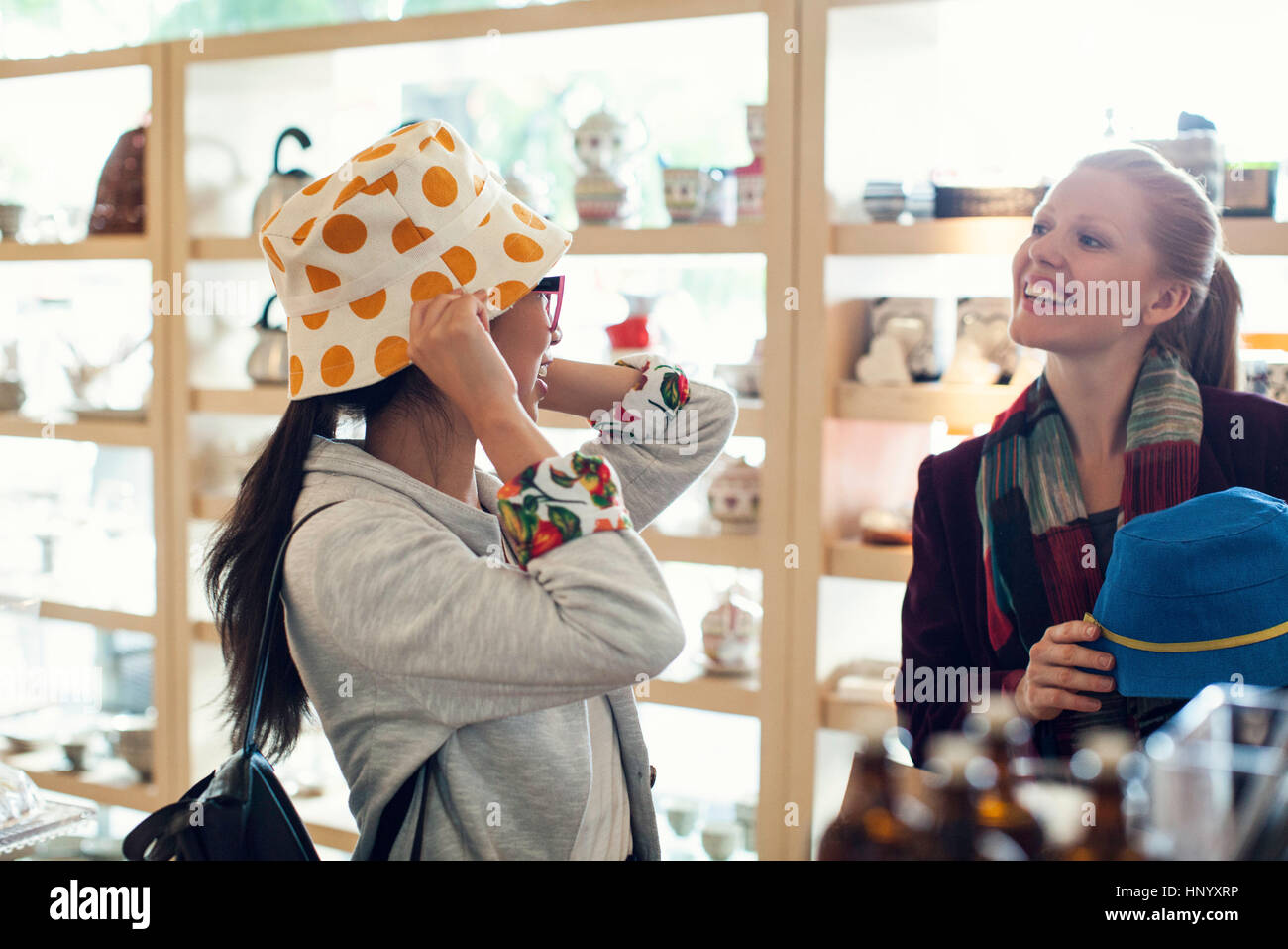 Woman trying on hat while shopping with friend Stock Photo