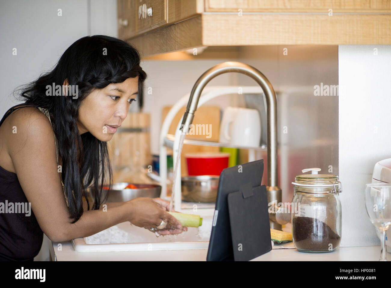 Woman using digital tablet while preparing food at home Stock Photo