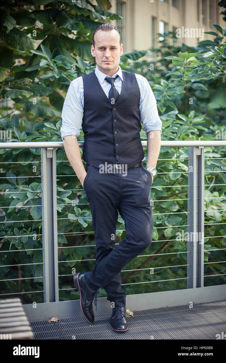 Well-dressed man standing on balcony, portrait Stock Photo