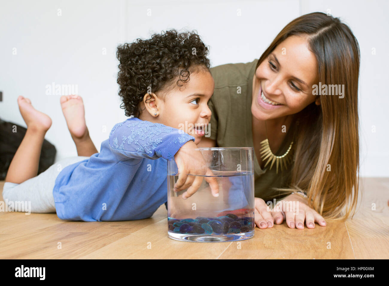 Mother and toddler daughter playing with pet goldfish Stock Photo