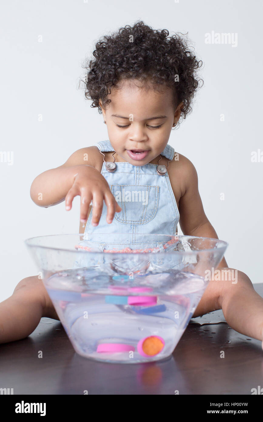 Toddler girl playing with toys in bowl of water Stock Photo
