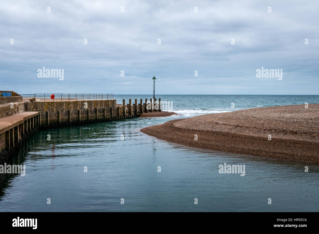 Narrow channel and sandbank where River Axe enters the sea at Axmouth harbour. Stock Photo