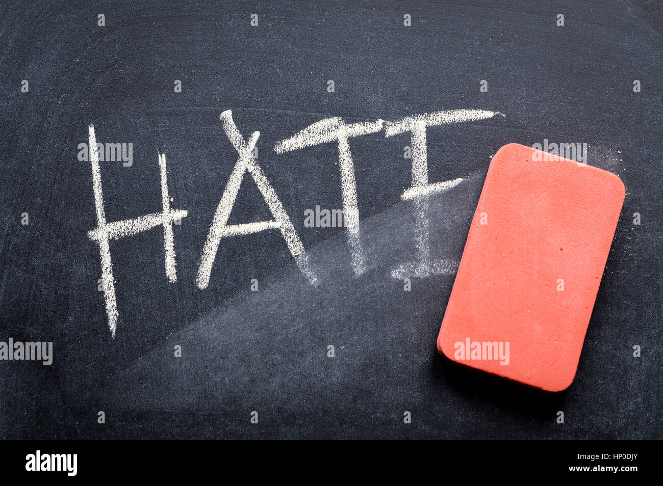 erasing hate, hand written word on blackboard being erased concept Stock Photo