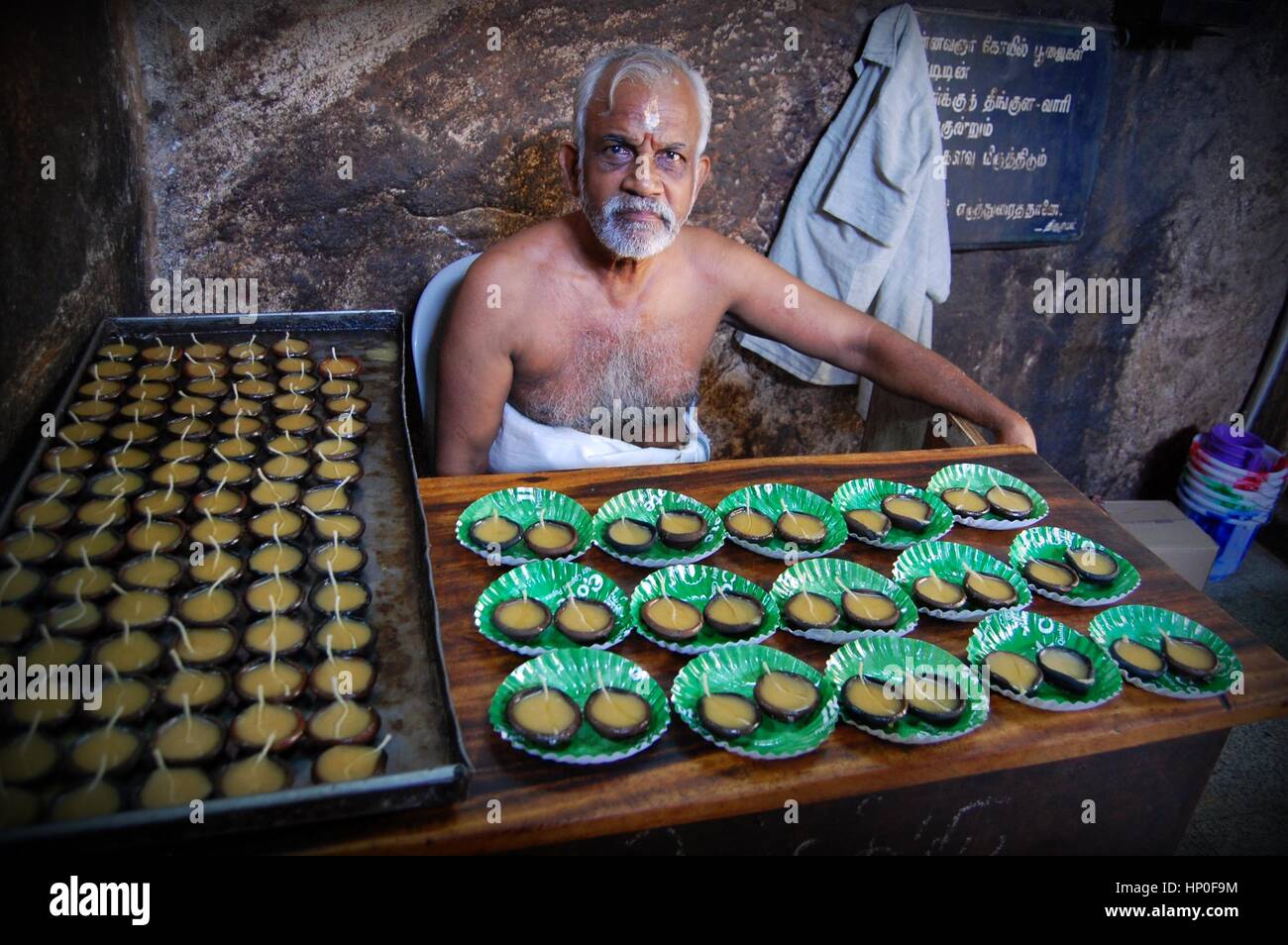 Indian man selling votive candles for visitors to the shrines at the