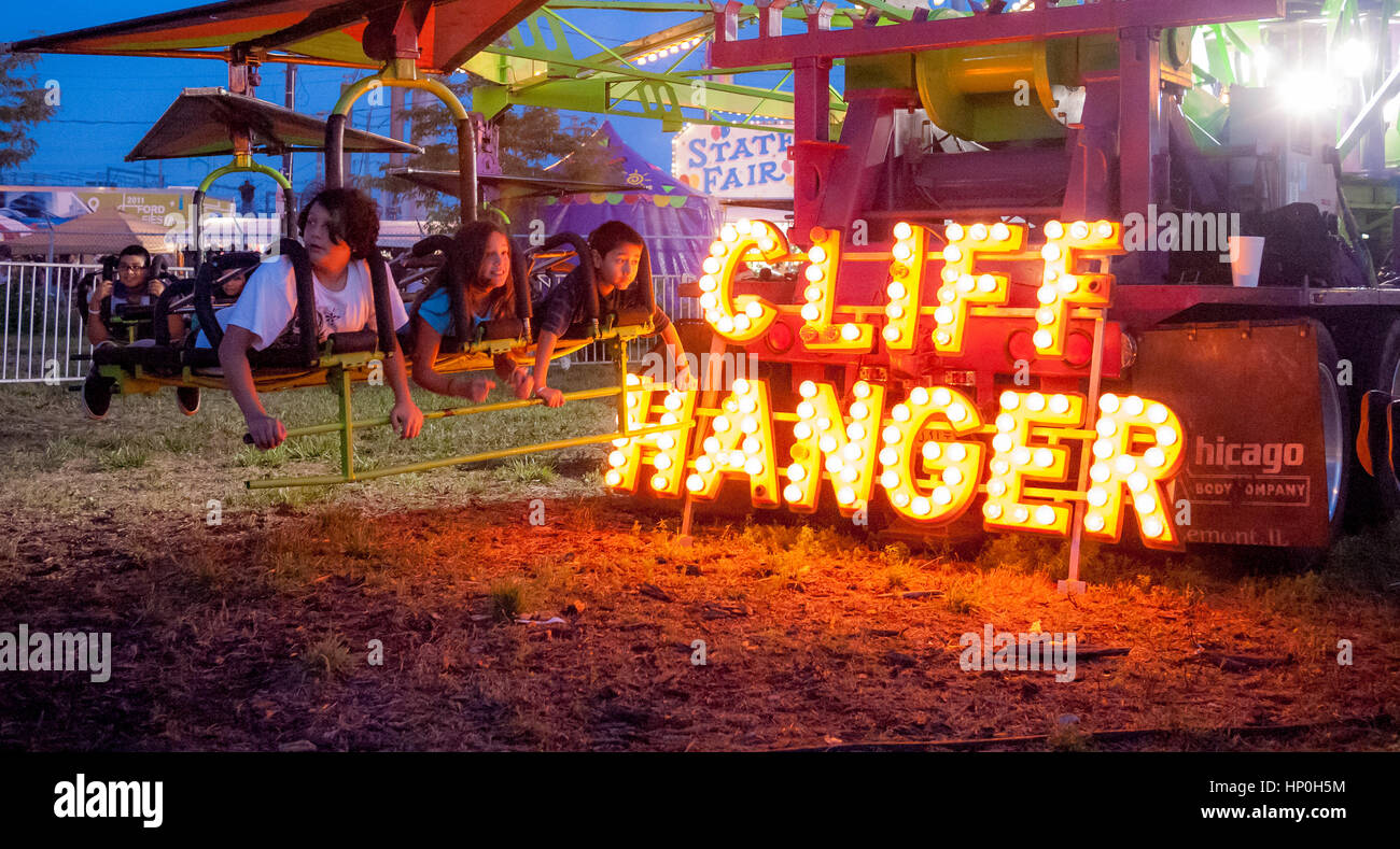 Children on an amusent park ride called the 'Cliff Hanger' at dusk on the South Side of Chicago, Illinois. Stock Photo