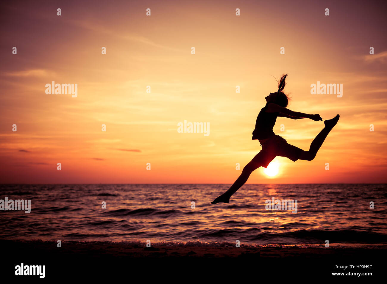 Happy teen girl jumping on the beach at the sunset time Stock Photo Alamy