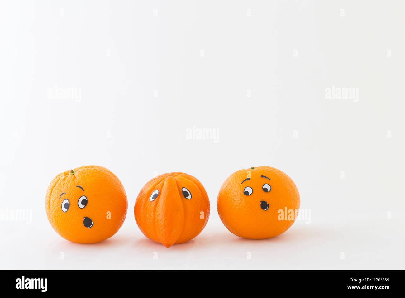 Fresh oranges with funny faces in front of white background. One orange