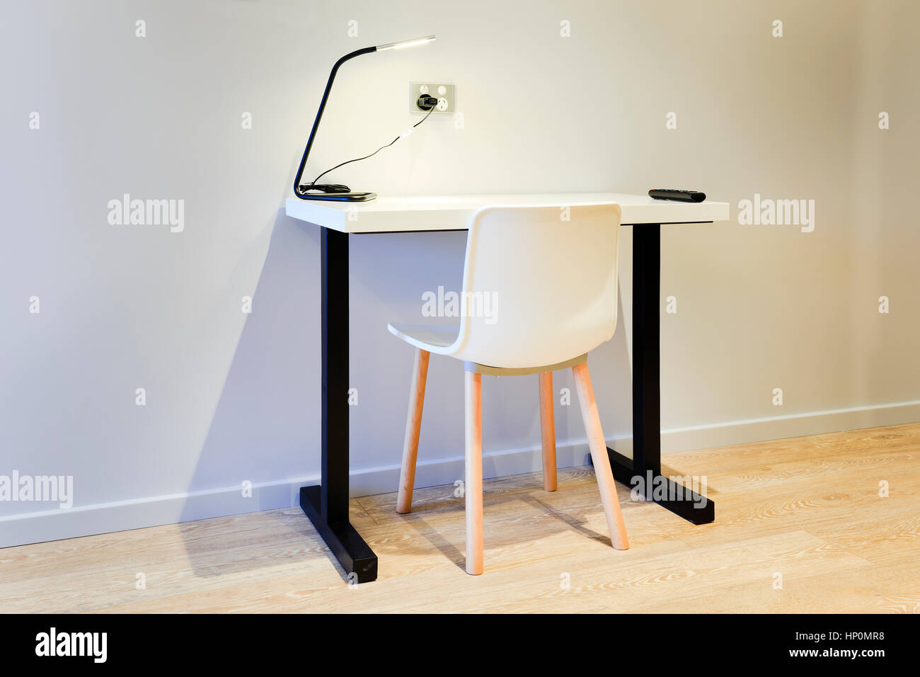 Single modern compact study computer desk with chair for laptop and education of students. Minimalistic design with table lamp and free space around. Stock Photo