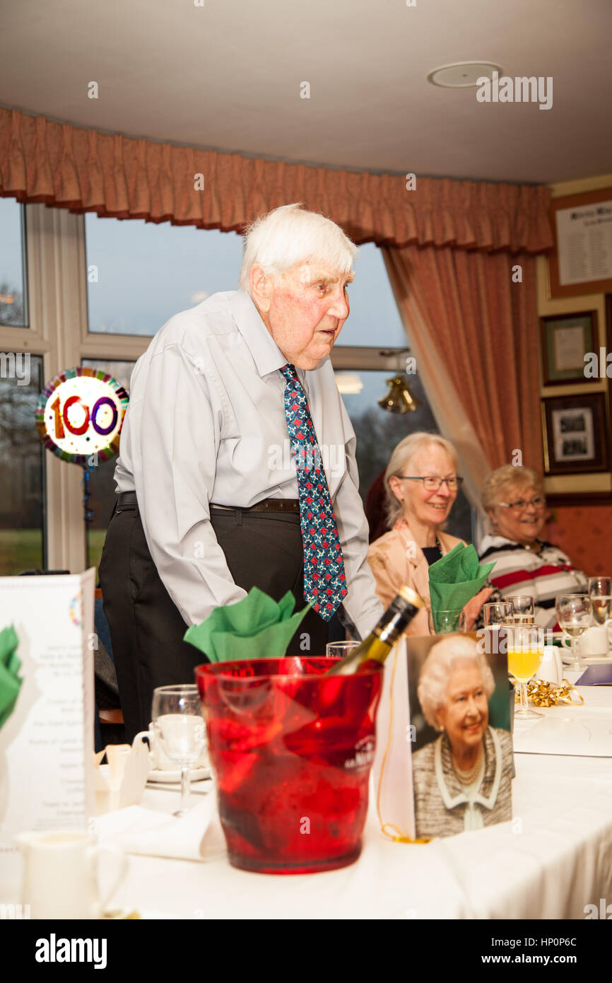 One hundred year old man celebrating at his birthday party at his local golf club with a birthday card from the Queen on the table in front of him Stock Photo