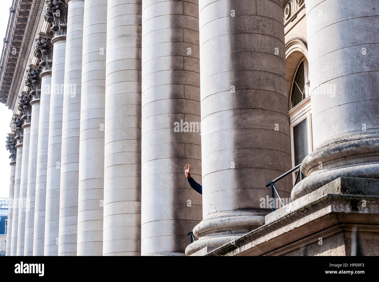 A hand waves from the Bourse frontage in Paris, France Stock Photo