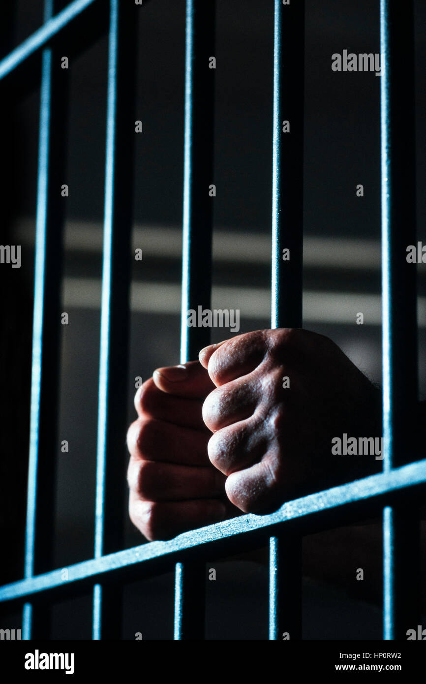 Hands grasping bars in jail Stock Photo