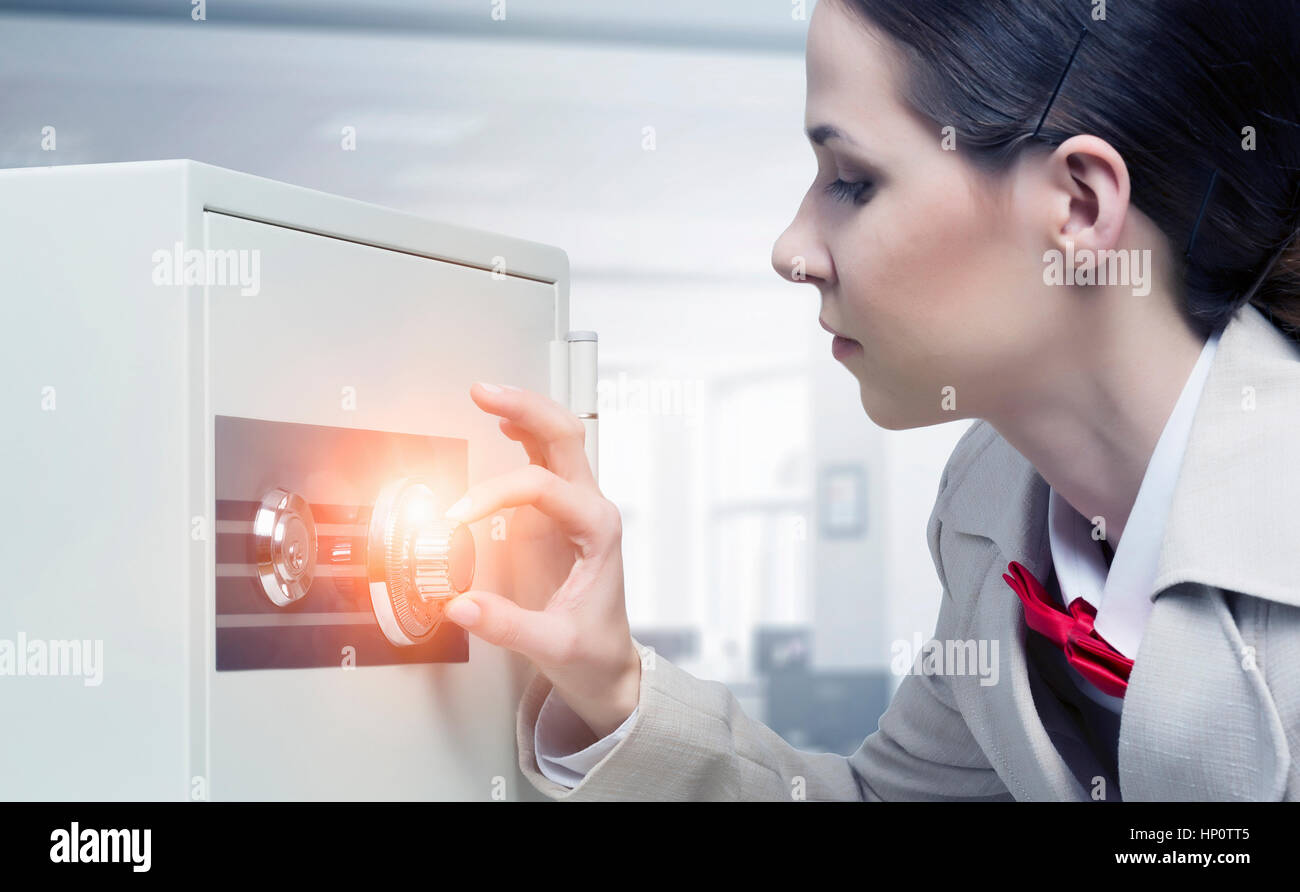 Young businesswoman dialing code on safe lock Stock Photo - Alamy