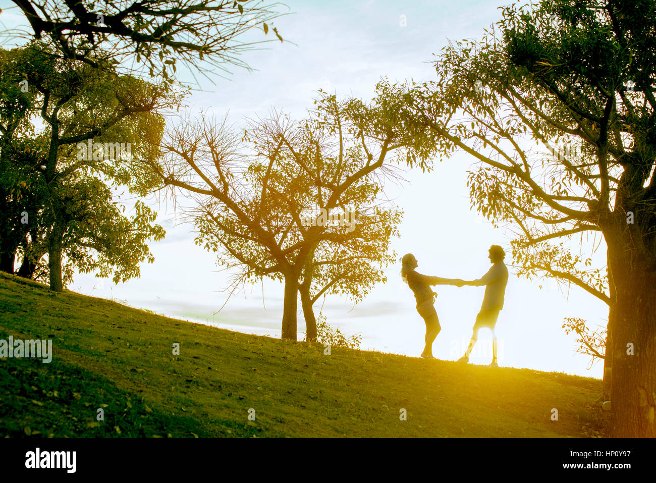 Couple holding hands in park, backlit by sunlight Stock Photo
