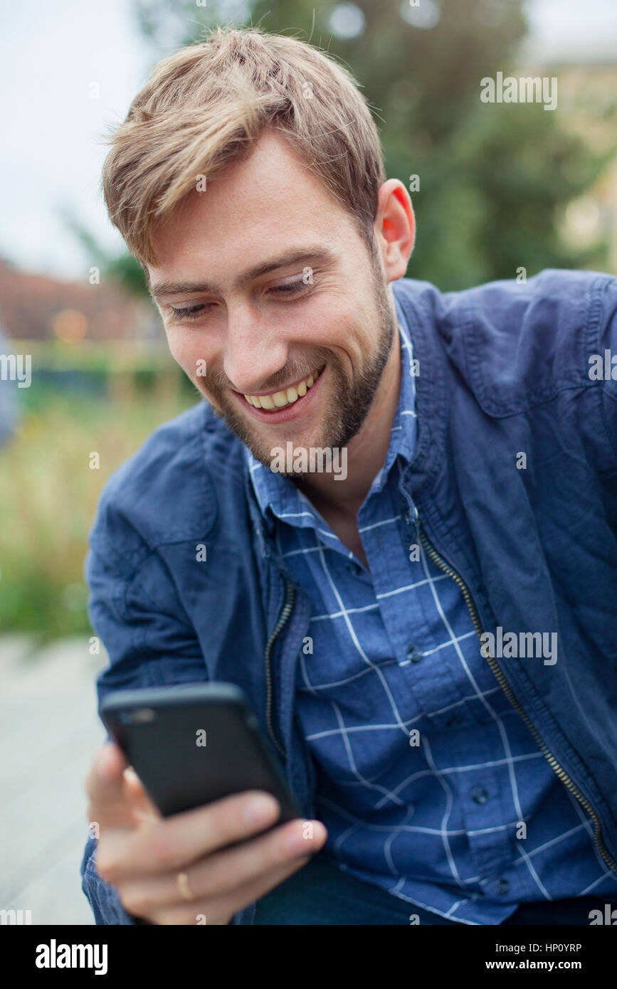 Young man text messaging with smartphone outdoors Stock Photo