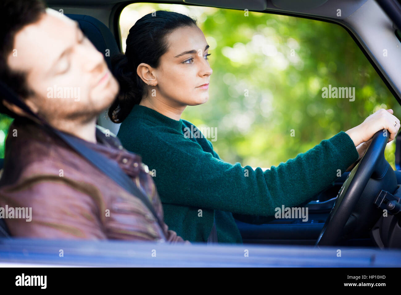 Woman driving while companion naps Stock Photo
