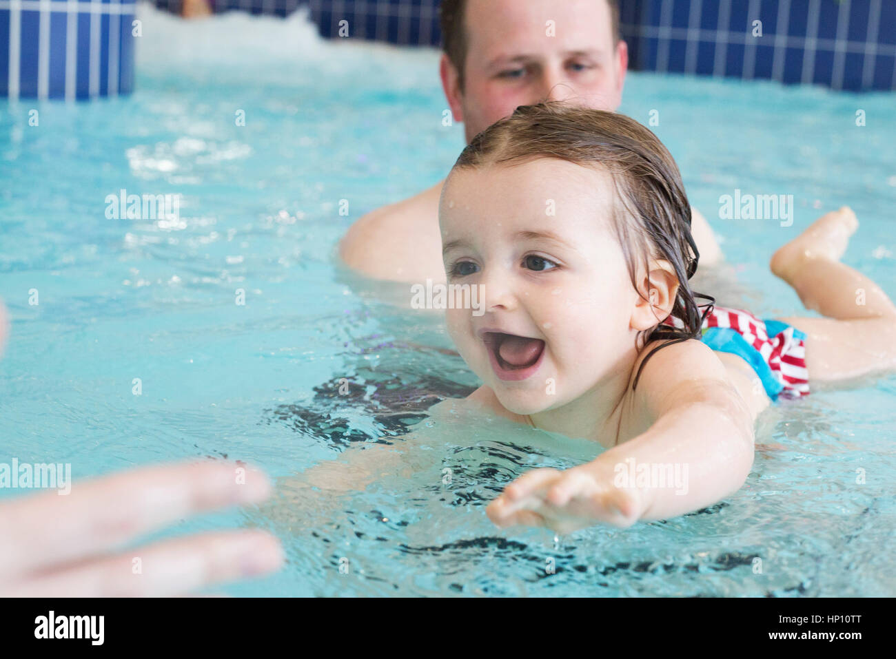 Little girl learning to swim with help of parent Stock Photo