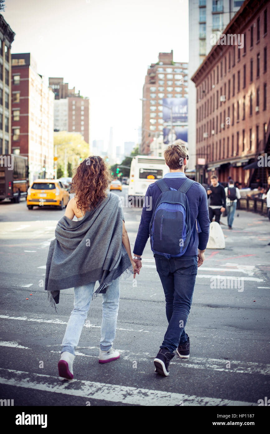 Couple crossing city street together, rear view Stock Photo
