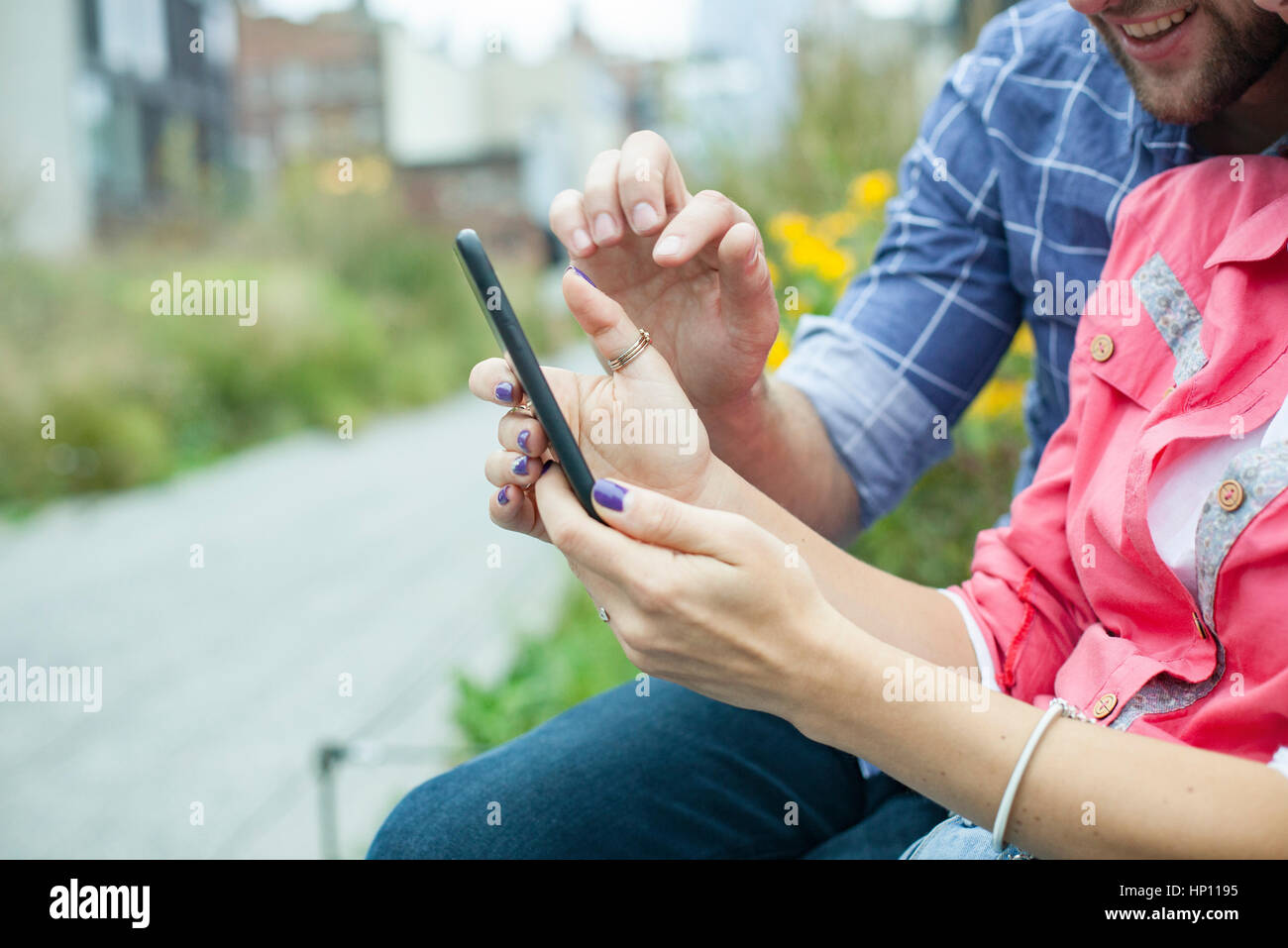 Couple using smartphone together outdoors Stock Photo