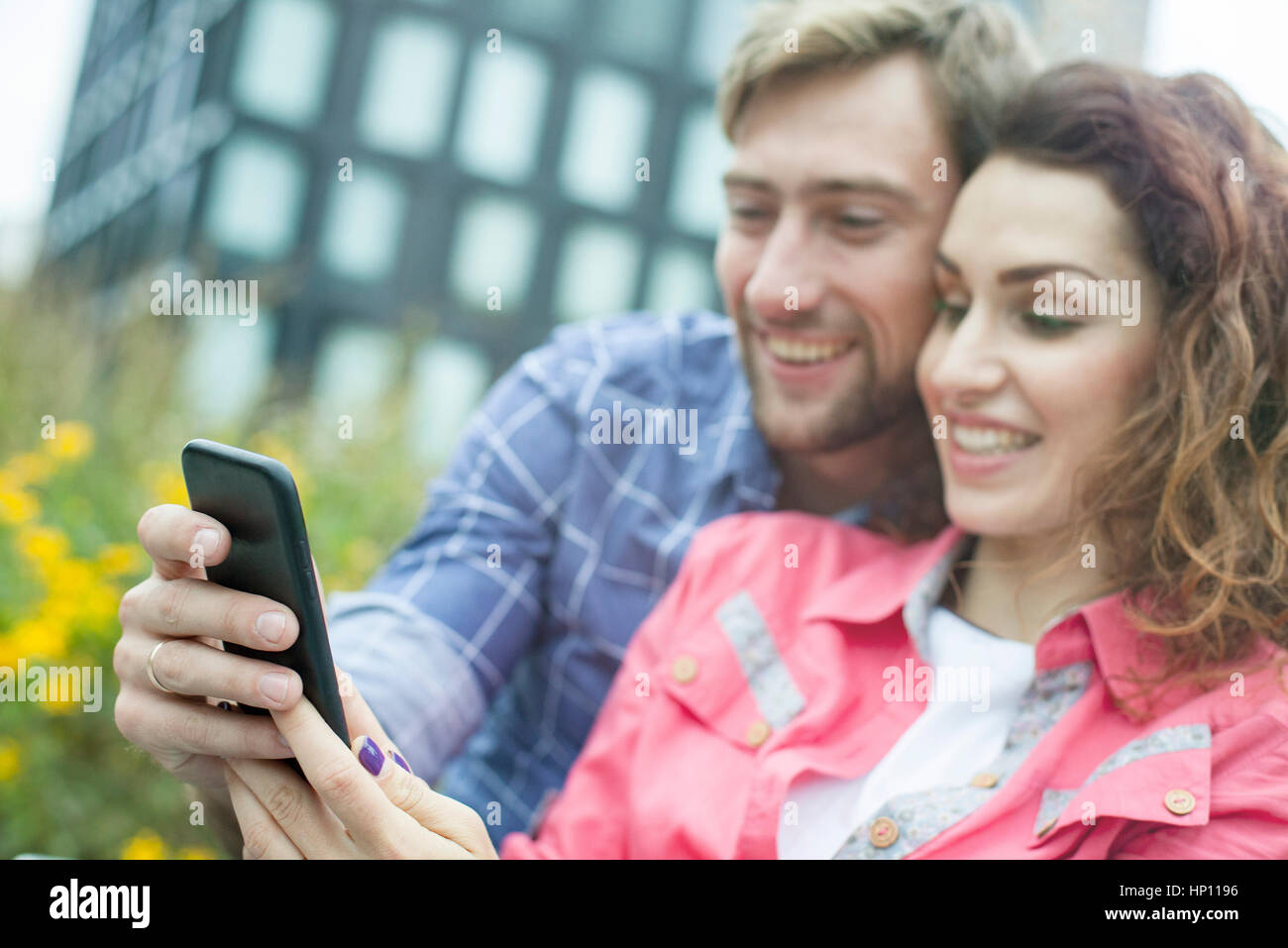 Couple using smartphone together outdoors Stock Photo