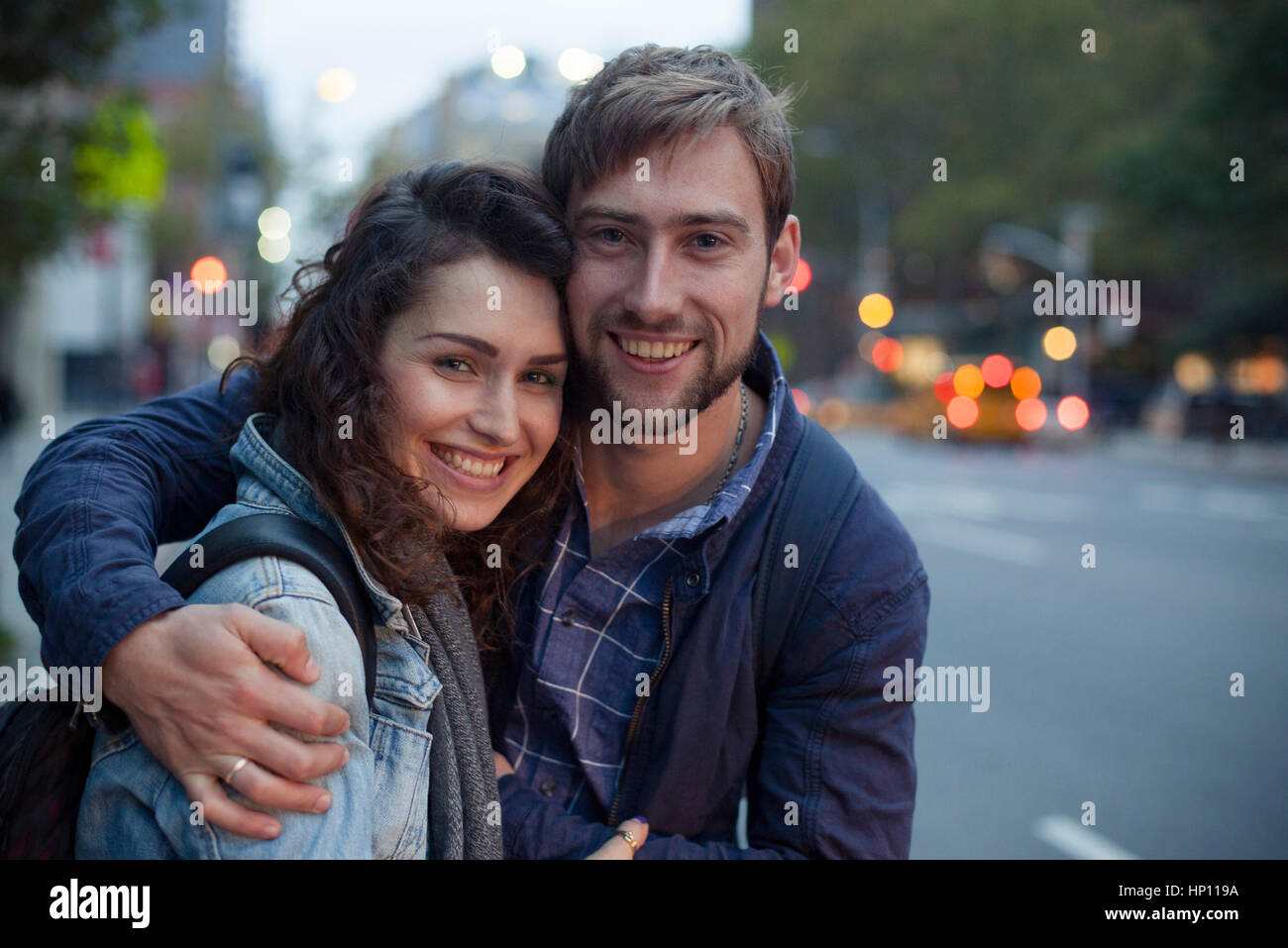 Young couple embracing on city street at night, portrait Stock Photo