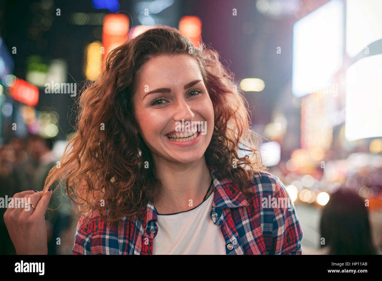 Young woman standing in illuminated city street Stock Photo