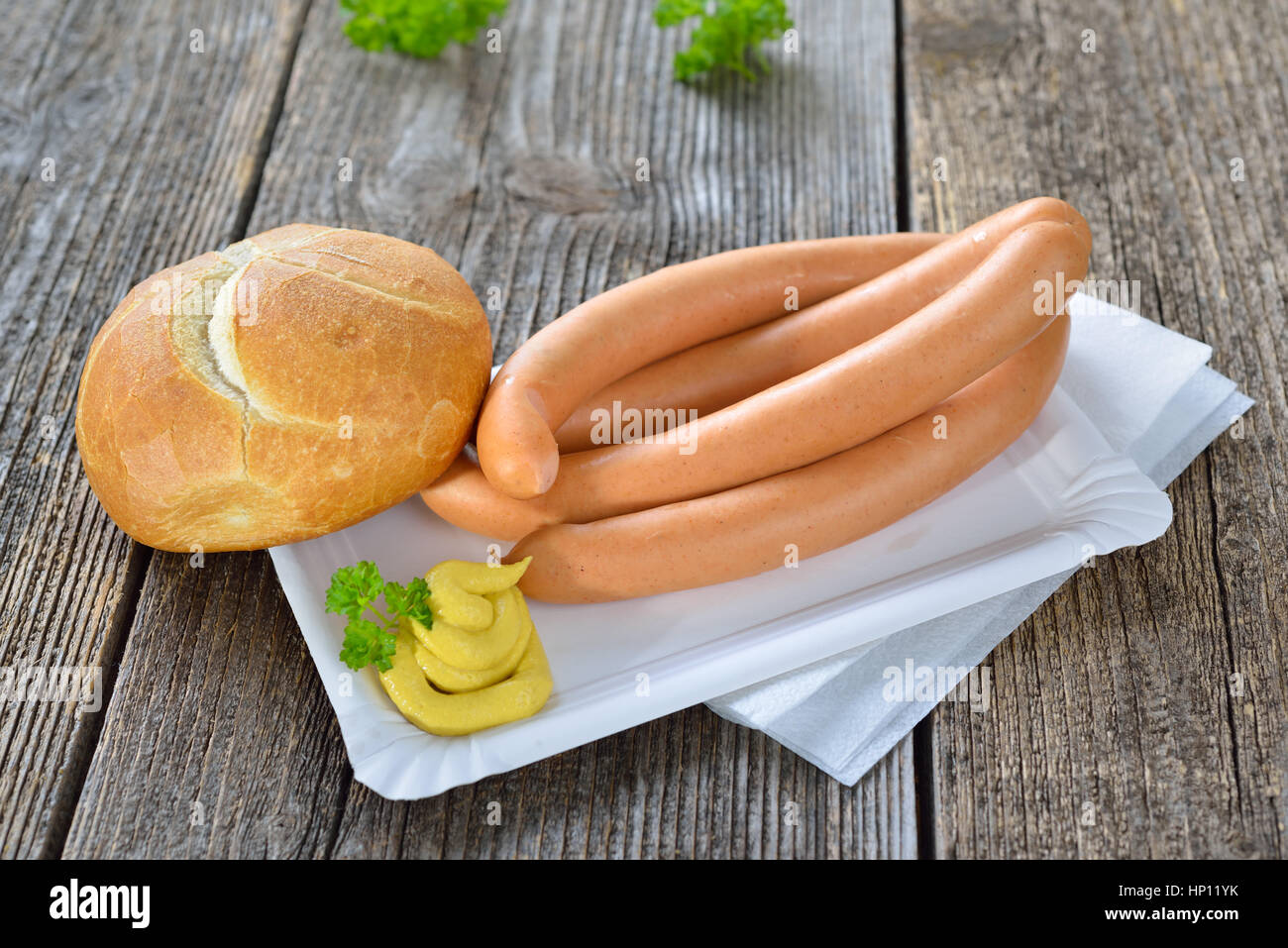 German street food Four wieners with a fresh roll and spicy mustard on a paper plate Stock