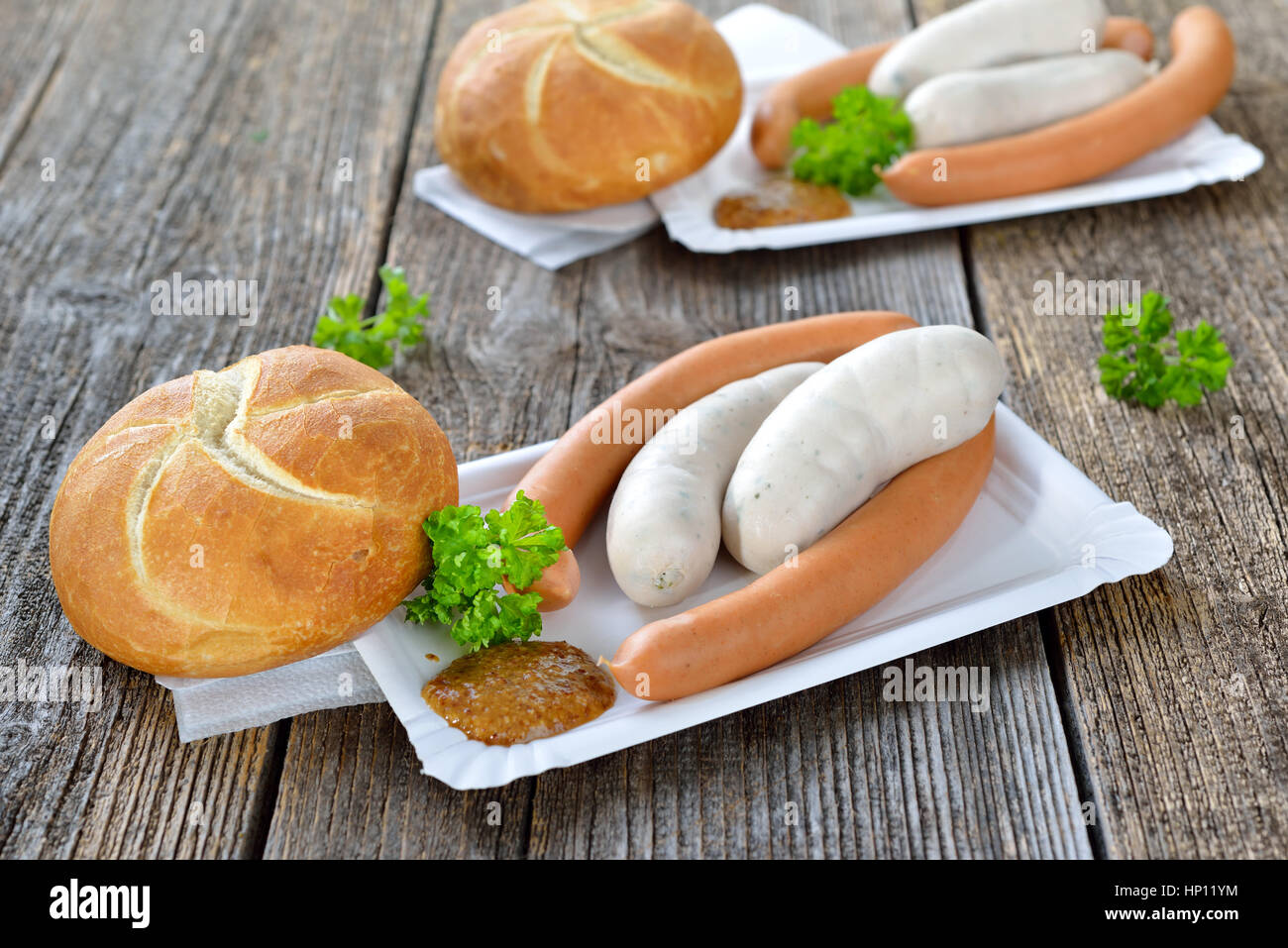 German street food: Bavarian white sausages and wieners with a fresh roll and sweet mustard on a paper plate Stock Photo