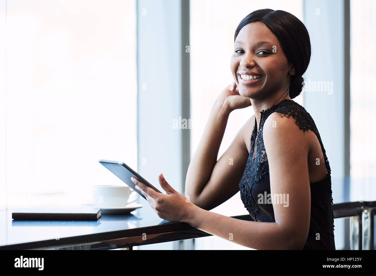 Happy young black woman smiling at the camera with tablet Stock Photo