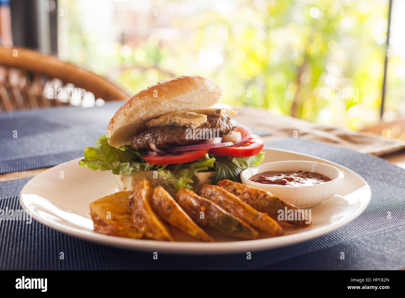 A Bleu (Blue) cheese hamburger with fries and barbecue sauce on a cafe