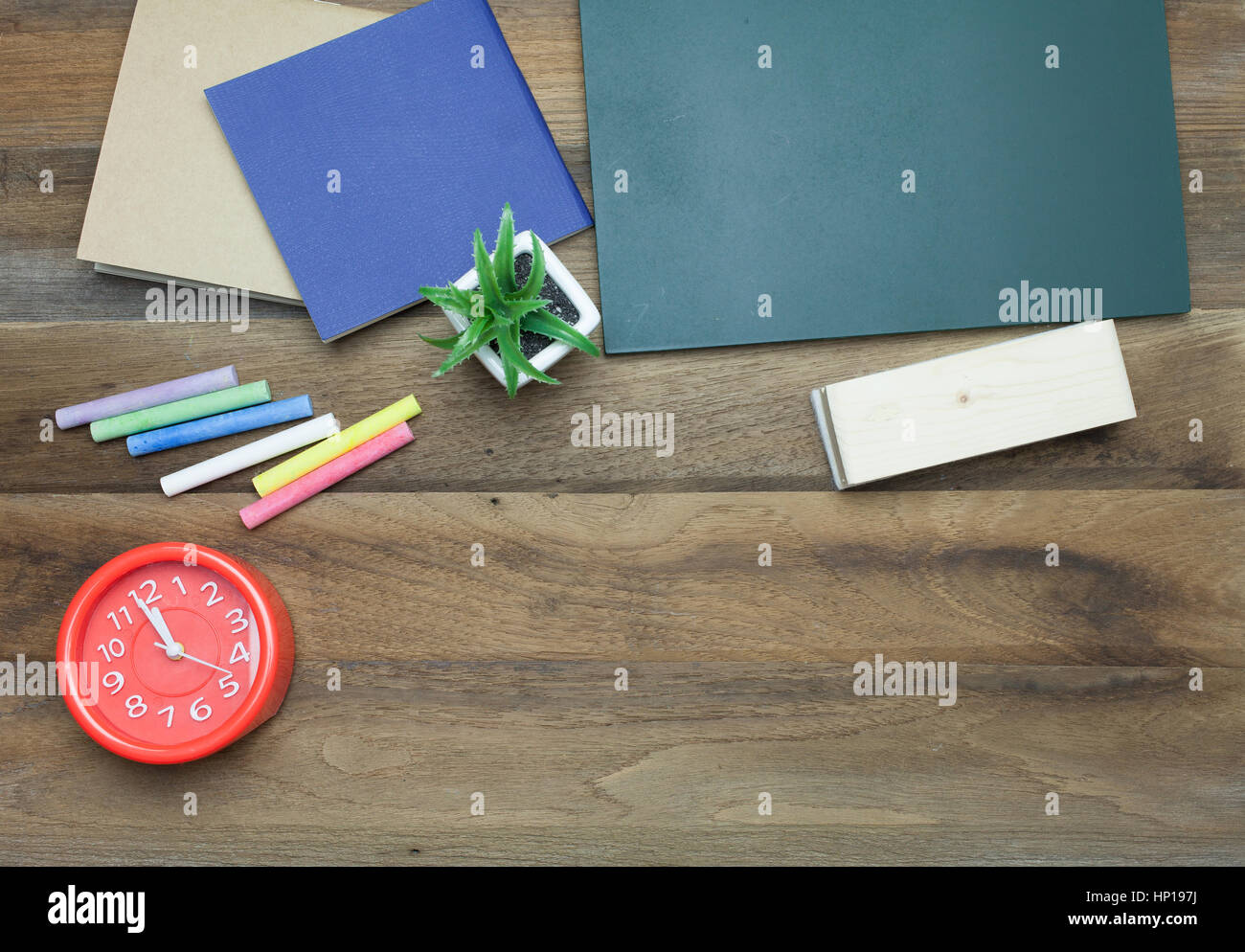 Red clock,Colorful Chalks,Chalk board,book and eraser on wooden background Stock Photo