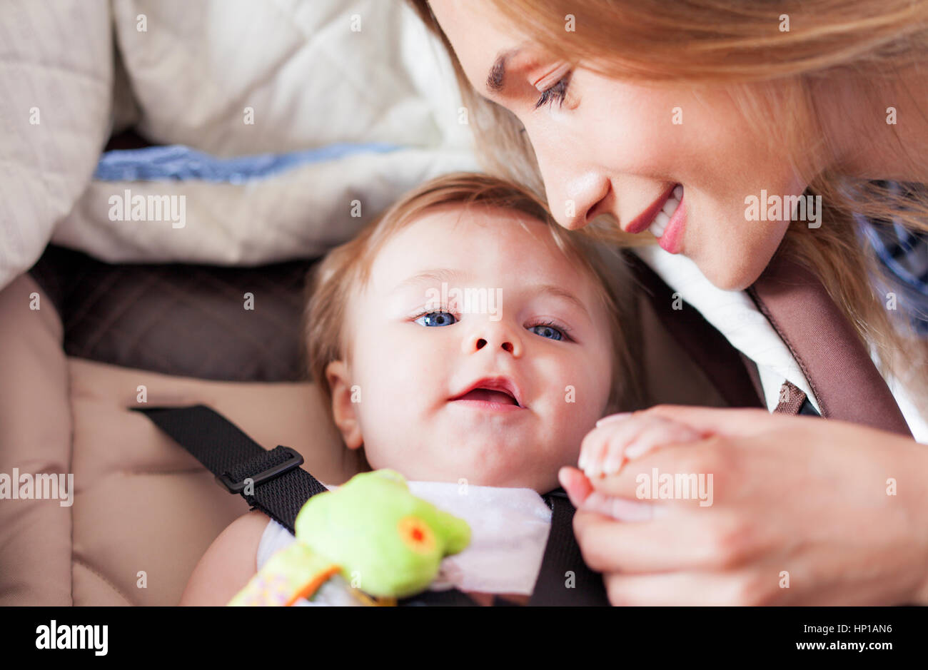 A loving mother is holding the small hand of her babe boy while he is smiling. Stock Photo