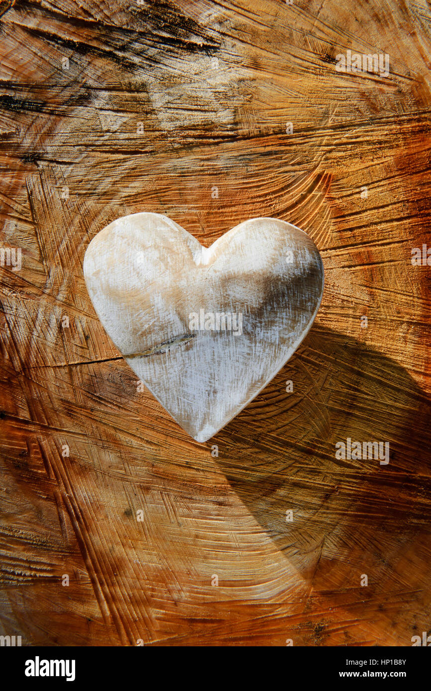 White painted wooden heart on roughly sawn tree stump Stock Photo