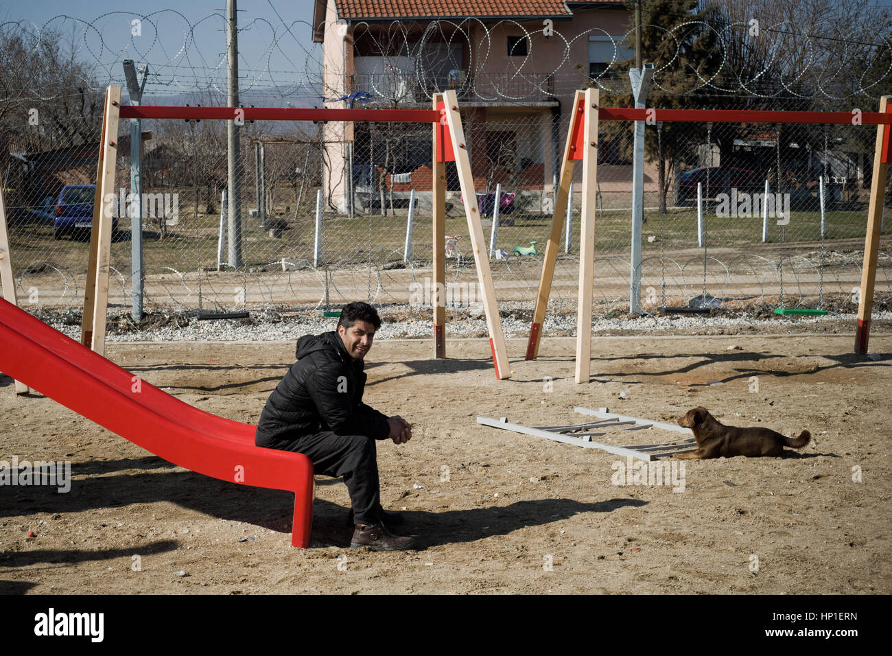 Tabanovce, Macedonia. 16th February 2017. Mohammad Shafi Abid from Kabul, Afghanistan, spends time sitting on a slide for refugee children at the Temporary Transit Center in Tabanovce, north Macedonia in the border with Serbia. Mohammad and his wife, 4 months pregnant, arrived at camp a month and a half ago after spending about $ 15,000 paid to smugglers. Smugglers robbed them, beat them up and abandoned them in the countryside when it began to snow. Mohammad  fled from Afghanistan after receiving death threats for working in Kabul for North American organizations. At the Temporary Transit Cen Stock Photo