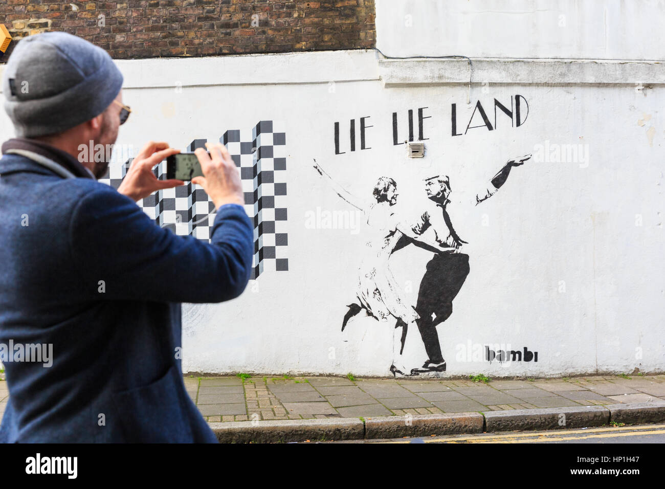 Islington, London, 17th Feb 2017. Passers-by look at a new graffiti by street artist Bambi which depicts US President Donald Trump and British PM Theresa May dancing in 'Lie Lie Land', a reference to the acclaimed film 'La La Land'. The work appeared this week on a side street in Islington. Credit: Imageplotter News and Sports/Alamy Live News Stock Photo