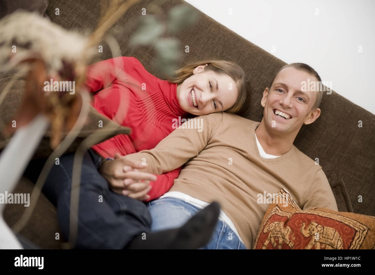 Model release , Liebespaar sitzt gemeinsam auf der Couch - love couple sitting on a couch at home Stock Photo