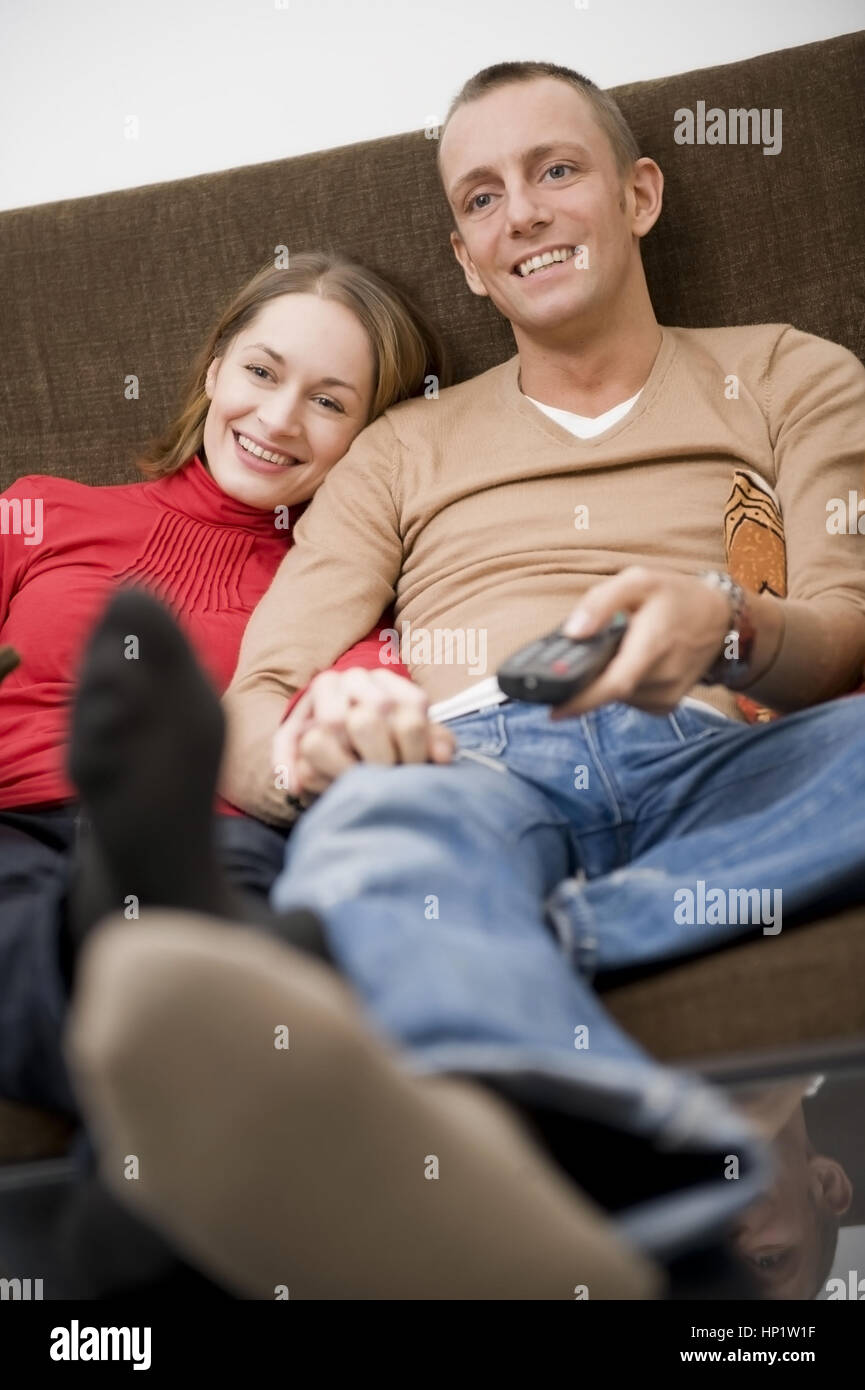 Model release , Paar auf der Cocuh beim fernsehen - couple watching TV on a couch Stock Photo