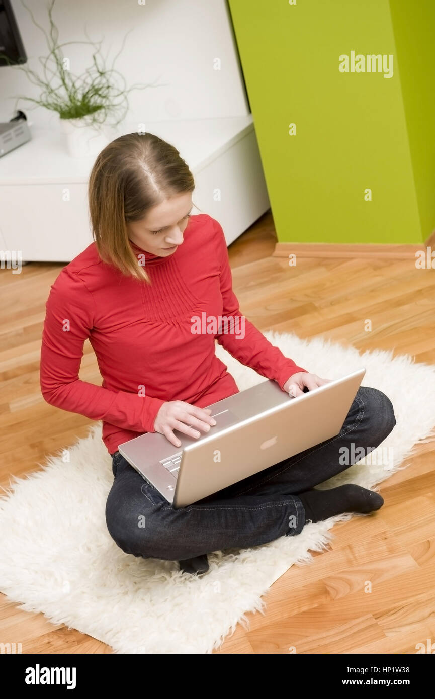 Model release , Junge Frau sitzt mit Laptop in Wohnraum - young woman with laptop Stock Photo
