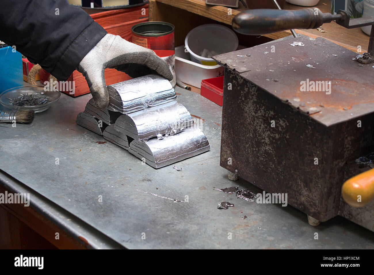 Manufactory, manual manufacturing of lead alloy. Melted alloy bars stacked in a pyramid on a workbench. Stock Photo