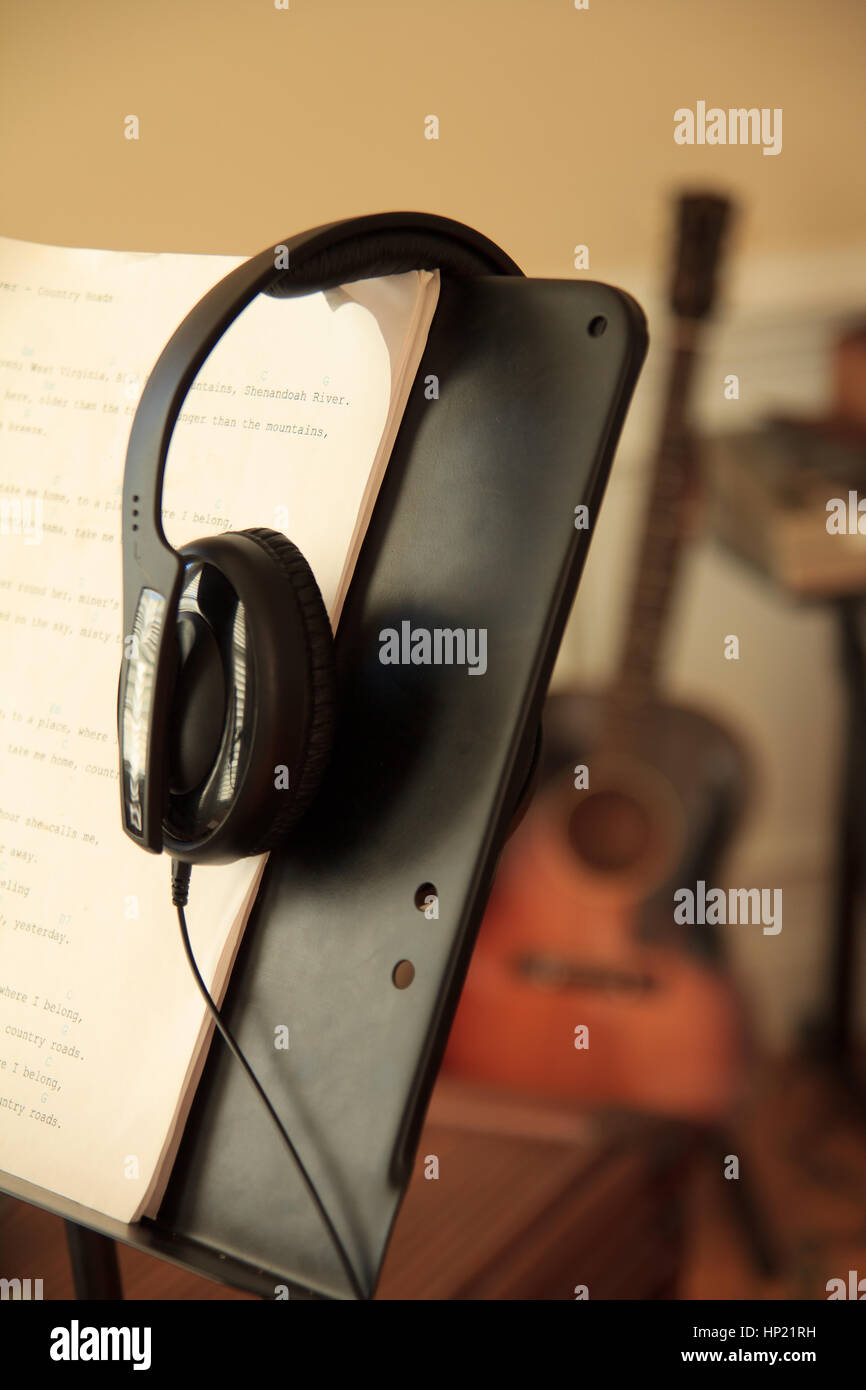 Headphones on music stand guitar in background out of focus Stock Photo