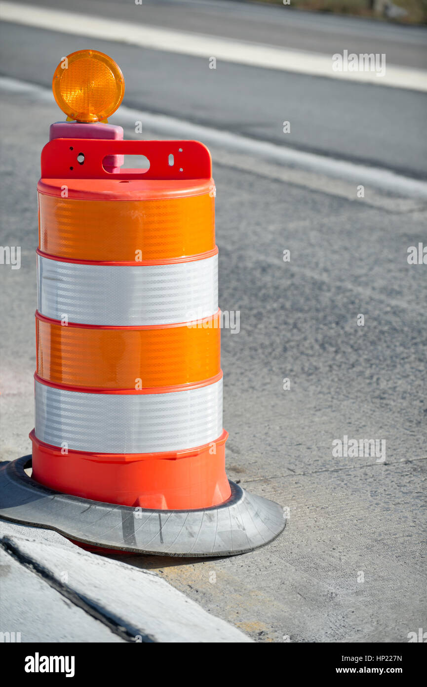 Orange barrels in highway construction zone as used in road maintenance and repair when creating traffic lane to guide drivers, summer morning side li Stock Photo