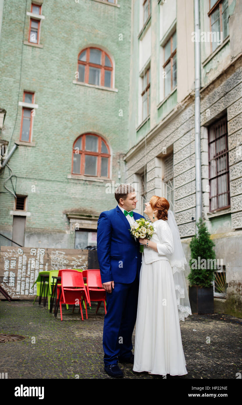 Wedding couple in love at yard of old street town background coloured chairs. Stock Photo