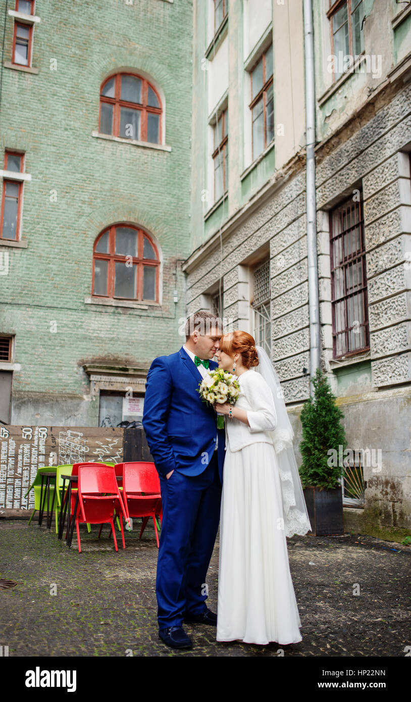 Wedding couple in love at yard of old street town background coloured chairs. Stock Photo